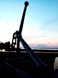 Close-up of old machinery on field against sky during sunset