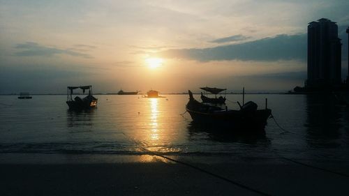 Boats in sea against sky during sunset