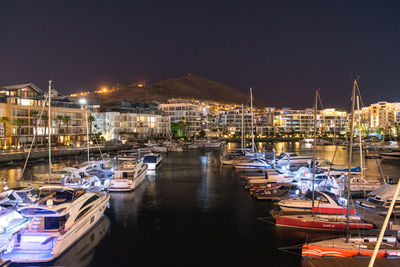Boats moored at harbor against sky at night