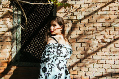 Portrait of woman standing against brick wall