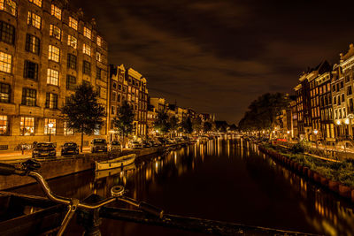 Canal amidst illuminated buildings in city at night