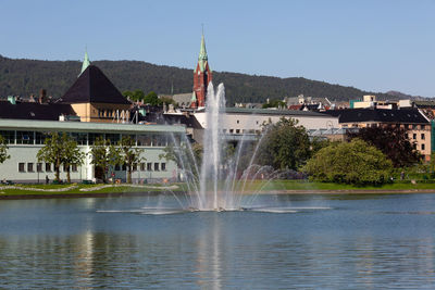 Fountain in city against clear sky