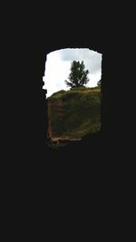 Silhouette landscape seen through arch against sky