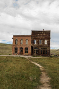 Abandoned buildings on field against sky in ghost town