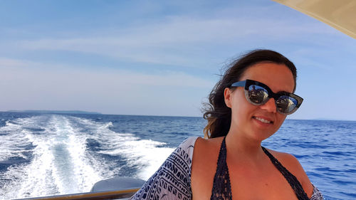 Portrait of smiling young woman in boat on sea against sky