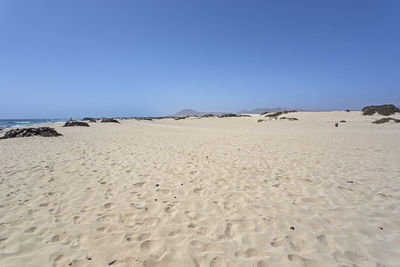 Scenic view of beach against clear blue sky