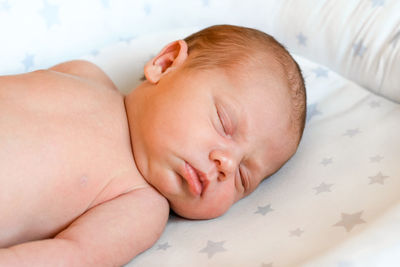 Closeup portrait of newborn baby sleeping on white.  one weeks old infant sleeping her side in bed