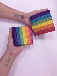 Cropped hands holding colorful ice cream sticks against wall