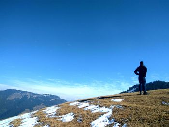 Rear view of man standing on snow covered landscape