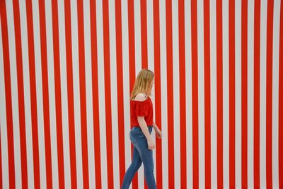 Rear view of woman standing against red wall