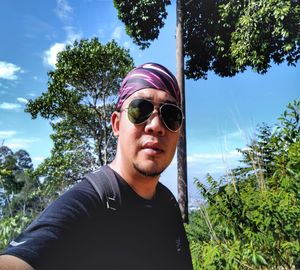 Portrait of young man wearing sunglasses against sky