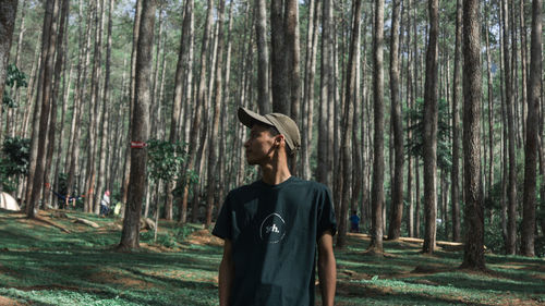 Man standing by trees in forest