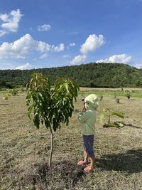 Rear view of person standing on field against sky