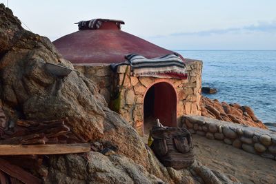 Old ruin of rock by sea against sky