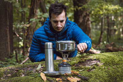 Man boils water for tea and food on portable stove and in a stainless steel ultralight pot