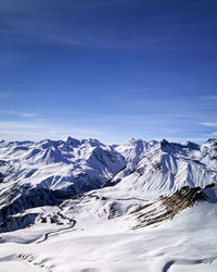 Scenic view of snowcapped mountains against blue sky