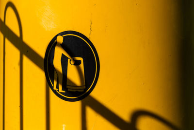 Close up of fence shadow on yellow litter bin with bin your litter logo