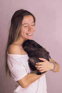 Portrait of young woman with dog against white background