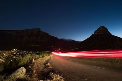 Light trails on road against clear sky at night