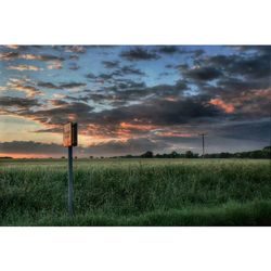 Scenic view of grassy field against cloudy sky