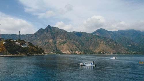 Scenic view of sea by mountains against sky