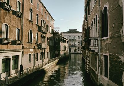 Canal amidst buildings against sky in city