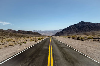 Empty road along landscape and mountains against sky