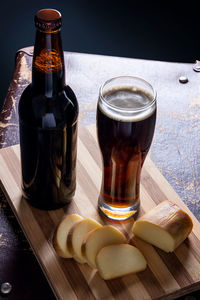 Beer in glass and bottle with cheese on table