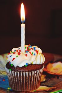 Close-up of illuminated candle on cupcake