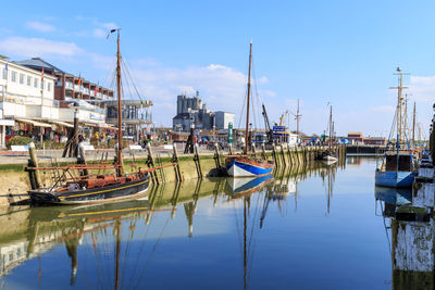 Sailboats moored at harbor against sky