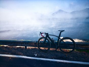 Bicycle by sea against sky