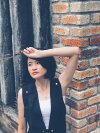 Portrait of woman standing against brick wall