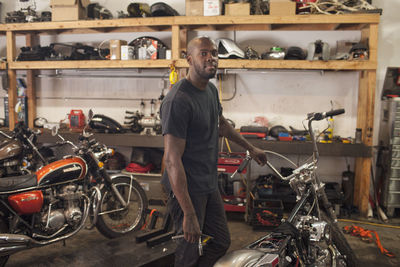 A young man in a garage with motoycles.