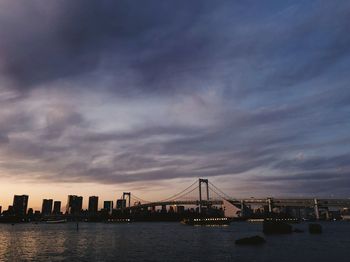 View of suspension bridge in city at sunset