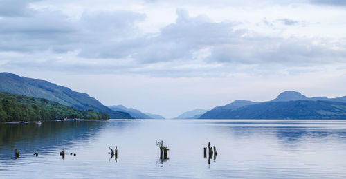 Scenic view of lake by mountains against cloudy sky