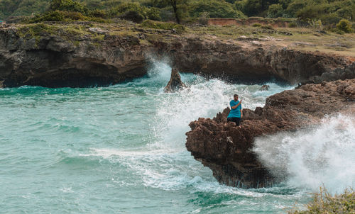 Man surfing on rock in sea