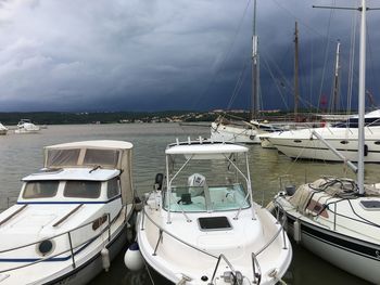 Boats moored at harbor against sky