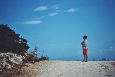Rear view of a man standing on sand at beach