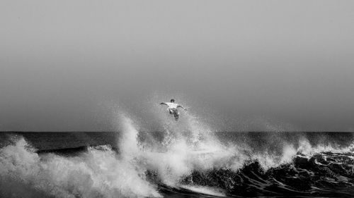 Man splashing water in sea against clear sky