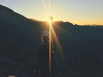 Man with umbrella against sky during sunset