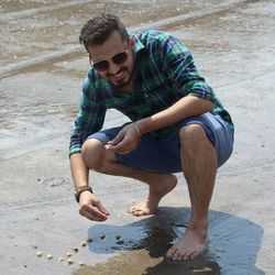 Happy man making letter j with stones at beach