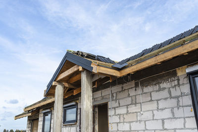 Ceramic tiles laid in packages on the roof on battens, visible concrete pillars at to the house.