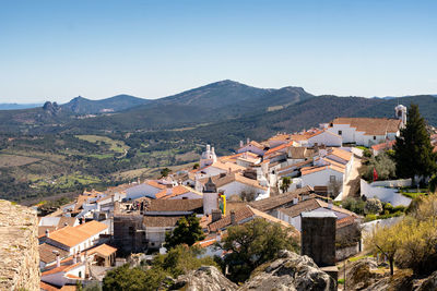 Townscape by mountains against clear blue sky