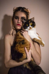 Portrait of woman with cat against colored background