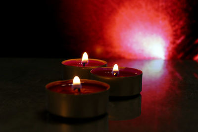 Close-up of lit candles on table in darkroom