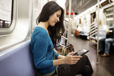 Side view of woman using tablet computer in train