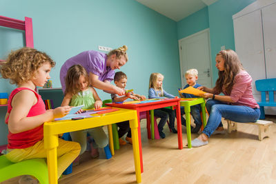 Cheerful teacher teaching children at classroom