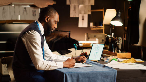 Side view of man using laptop at home