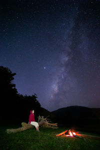 Full length of woman sitting on field against sky at night