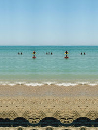 People on beach against clear sky